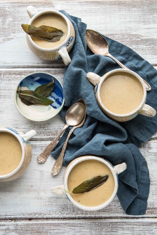 cluster of bowls of white bean and parsnip soup with blue linen napkin