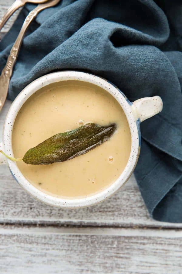 close up of fried sage leaf on white bean and parsnip soup