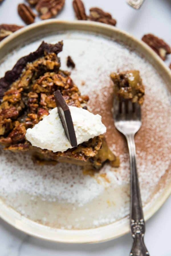 pie topped with whipped cream, chocolate and a forkful of bourbon pecan pie