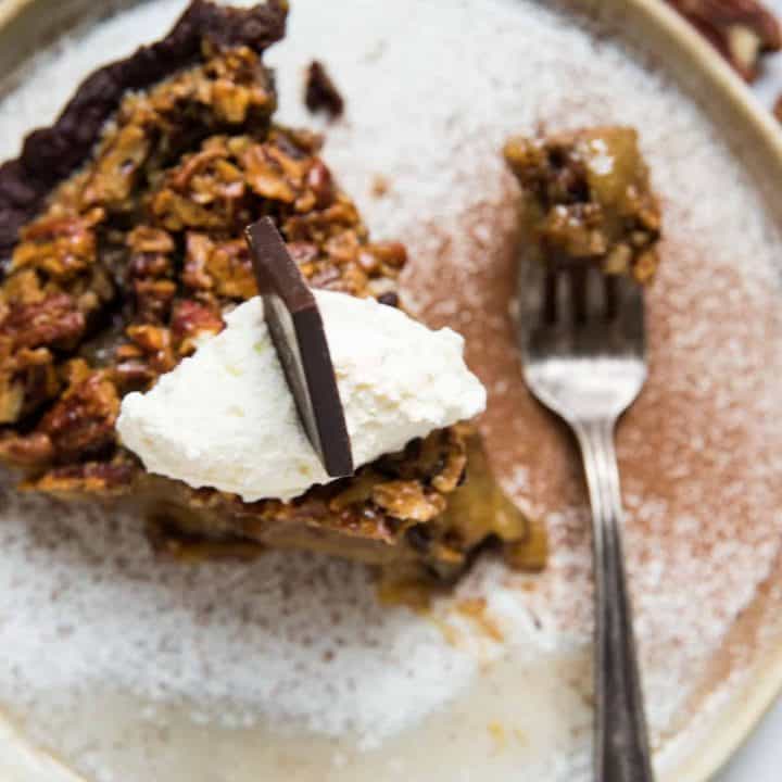 pie topped with whipped cream, chocolate and a forkful of bourbon pecan pie