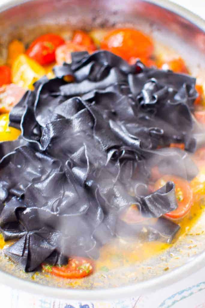 Fresh squid ink pasta out of the water and into the sauce