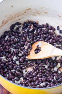 Yellow onion and black beans sautéed in bacon drippings for black bean soup.