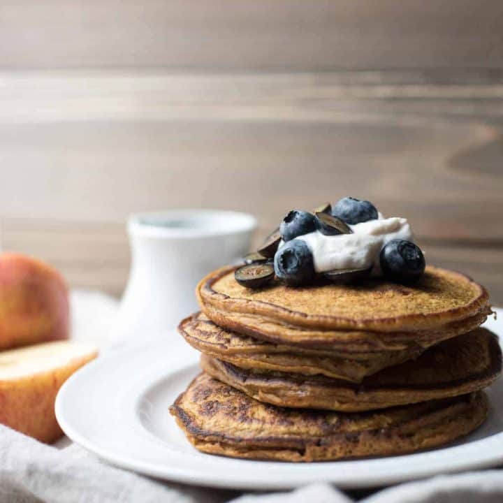 stack of pumpkin spice blender pancakes topped with yogurt and blueberries
