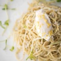 close up of ricotta on top of pesto spaghetti