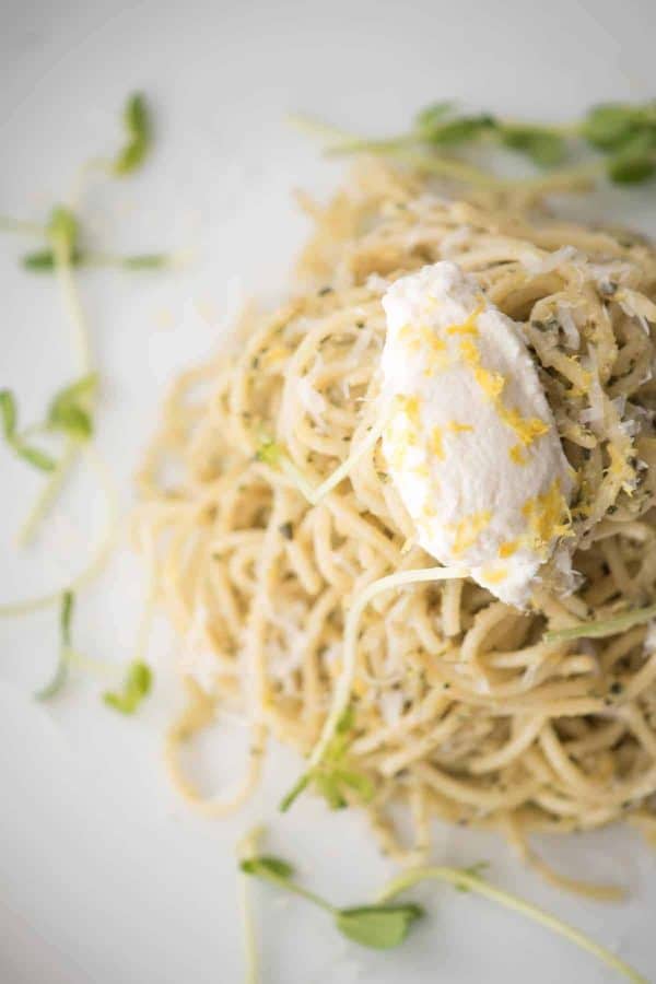 close up of ricotta on top of pesto spaghetti