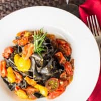 overhead view of squid in pasta with tomatoes in a bowl