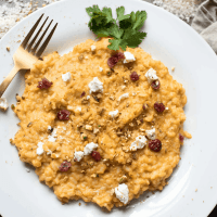Overhead view of pumpkin risotto with dried cranberries and goat cheese garnish