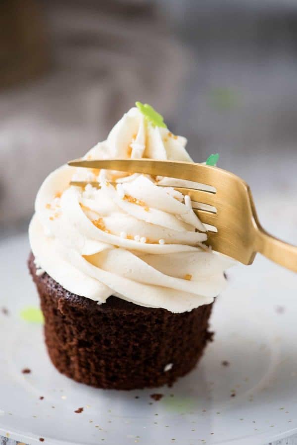fork slicing into frosting on a chocolate cupcake