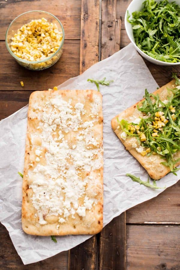 Simple Summer Flatbread with Grilled Corn, Arugula, Mascarpone + Goat Cheese. Just the right amount of crunch, creamy, sweet and savory - made in a flash!