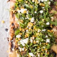 Simple Summer Flatbread with Grilled Corn, Arugula, Mascarpone + Goat Cheese. Just the right amount of crunch, creamy, sweet and savory - made in a flash!