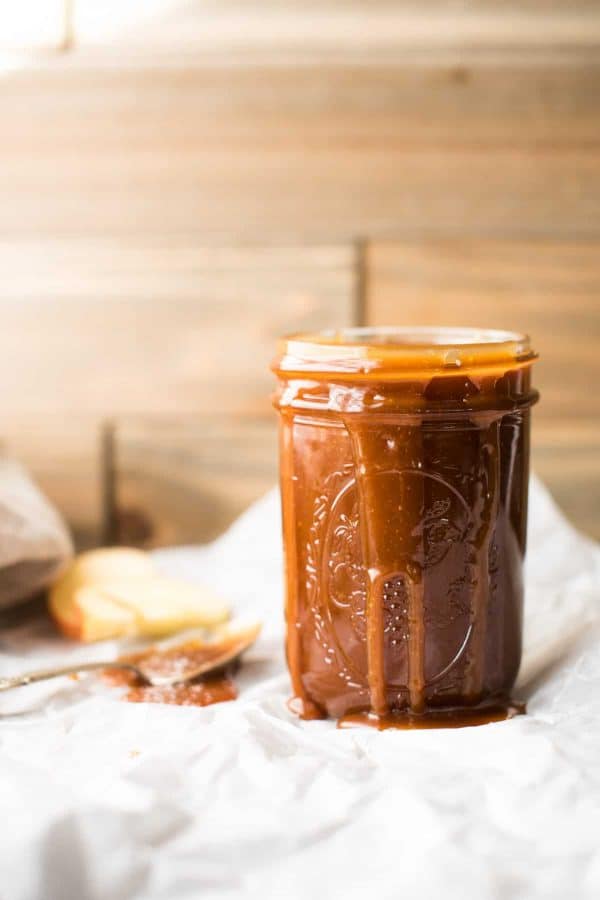 Jar of salted caramel sauce with gooey caramel drips down the side.