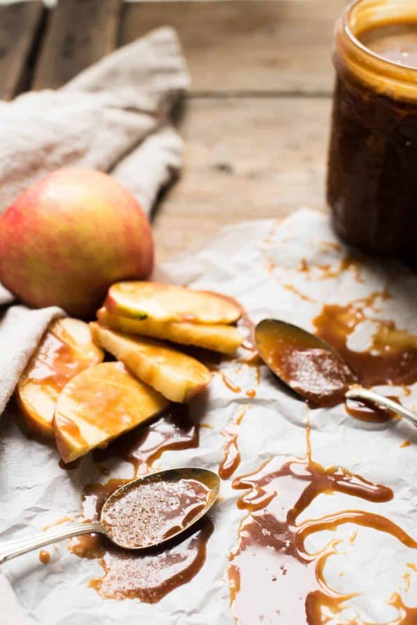 Spoons and apple slices covered in gooey salted caramel sauce