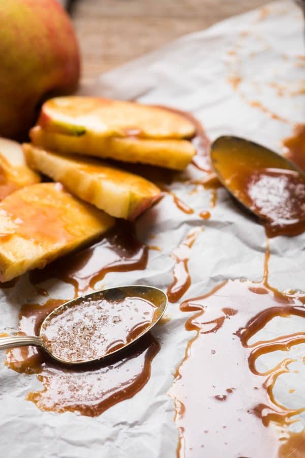 Spoons and apple slices covered in gooey salted caramel sauce