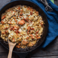 scooping lobster gratin out of a cast iron pan