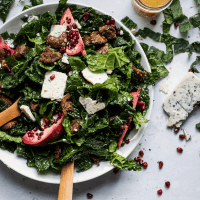 kale salad with pomegranate and blue cheese in a bowl