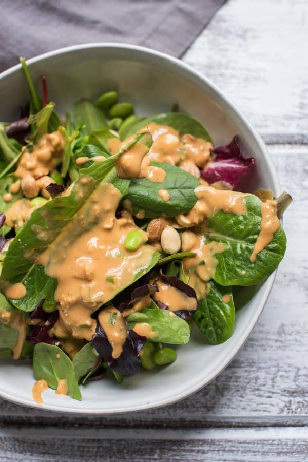 close up of thai peanut dressing on top of an easy green salad