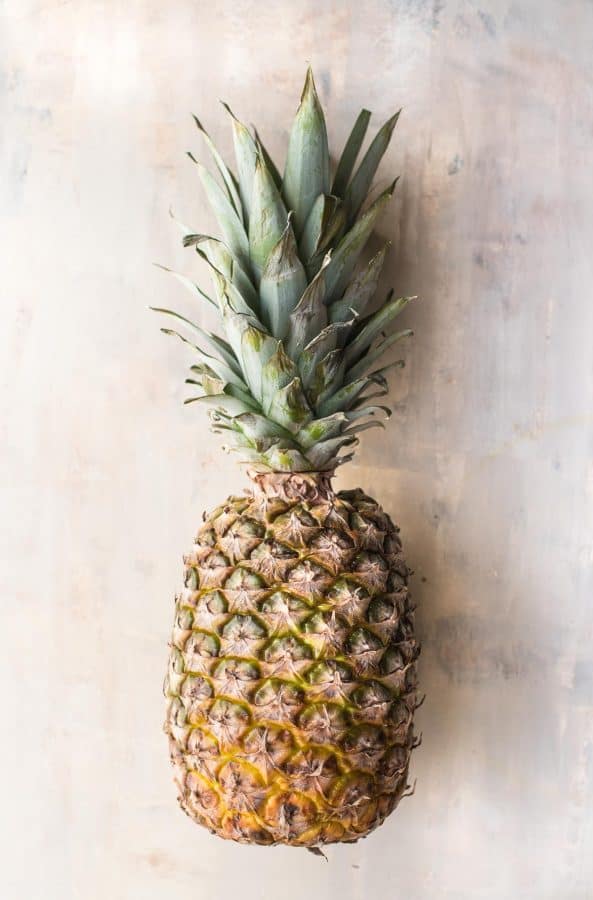fresh whole pineapple on a cream colored backdrop