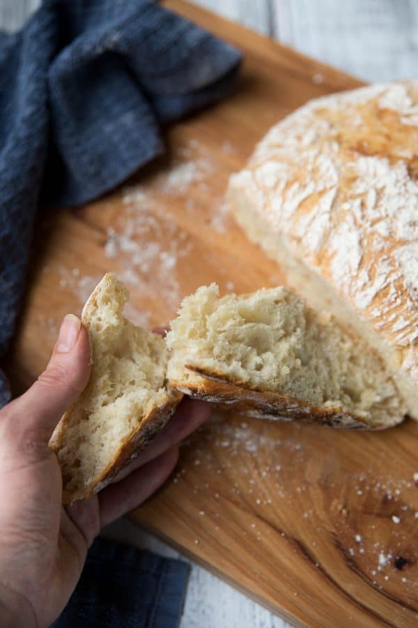 hand tearing into crusty french bread