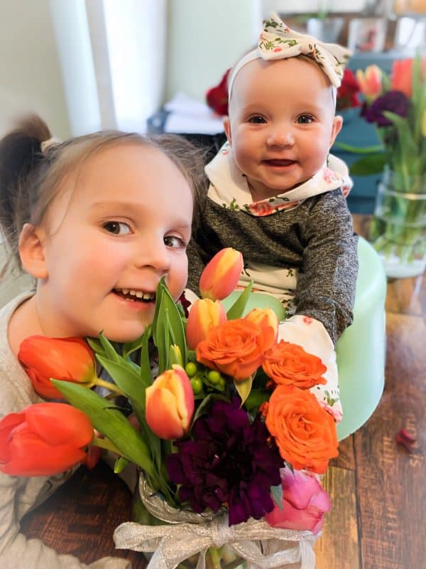 two small kids smiling with flowers