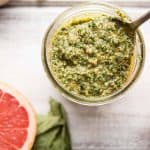 Spoon scooping grapefruit basil pecan pesto out of a jar