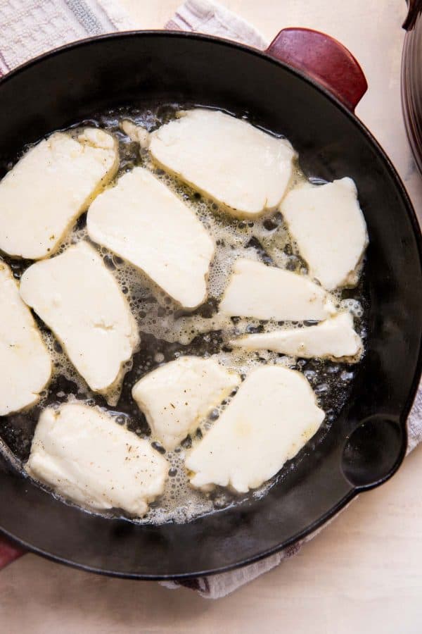 halloumi cheese frying in a cast iron skillet