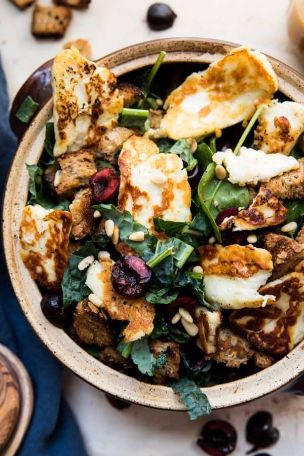 kale and spinach with cherries and fried halloumi in a bowl