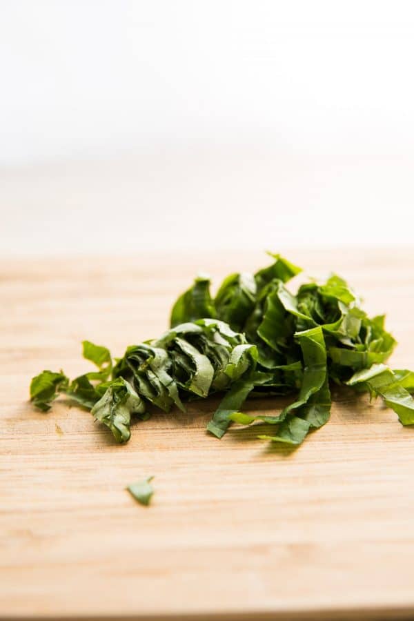 chiffonnade basil on a cutting board.