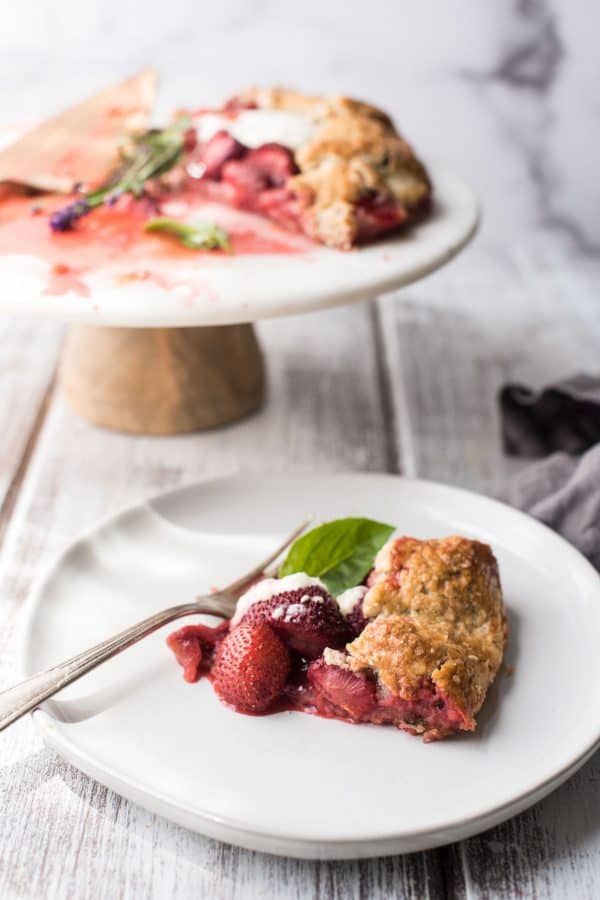 slice of strawberry galette on a plate with the rest on a pie stand