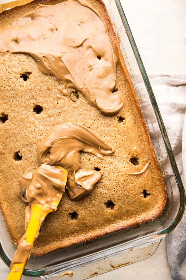 spreading creamy peanut butter into poke cake