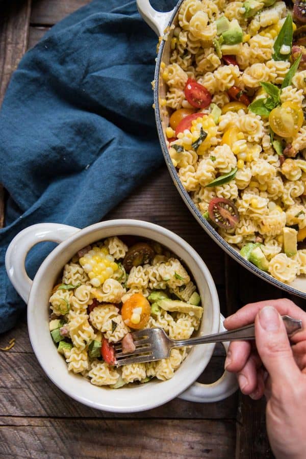 hand scooping out a forkful of pasta salad