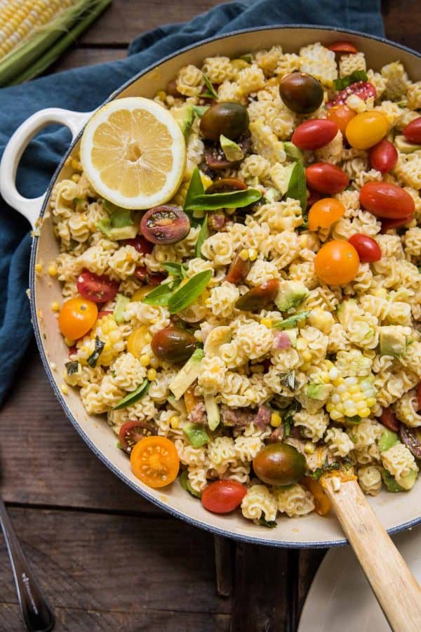 summer pasta salad in serving bowl with wooden spoon