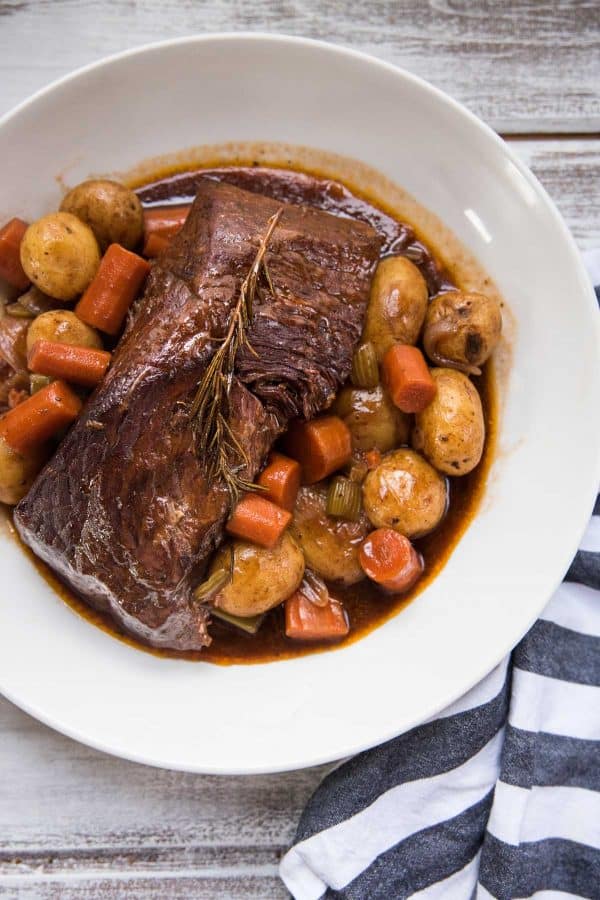 pot roast with vegetables and gravy in a serving platter