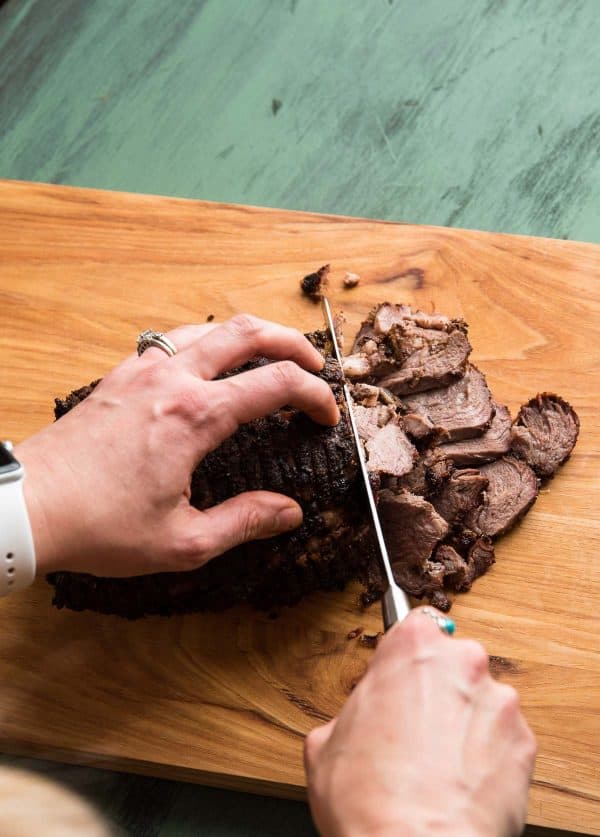 slicing lamb roast into thin pieces for gyros