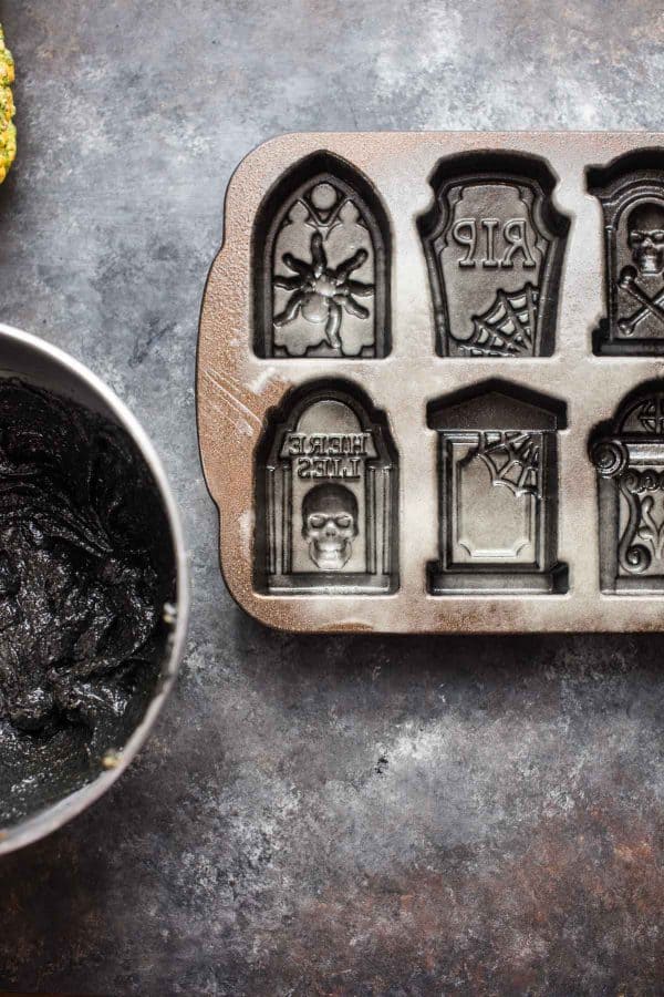 overhead photo of black cake batter and tombstone cake pan