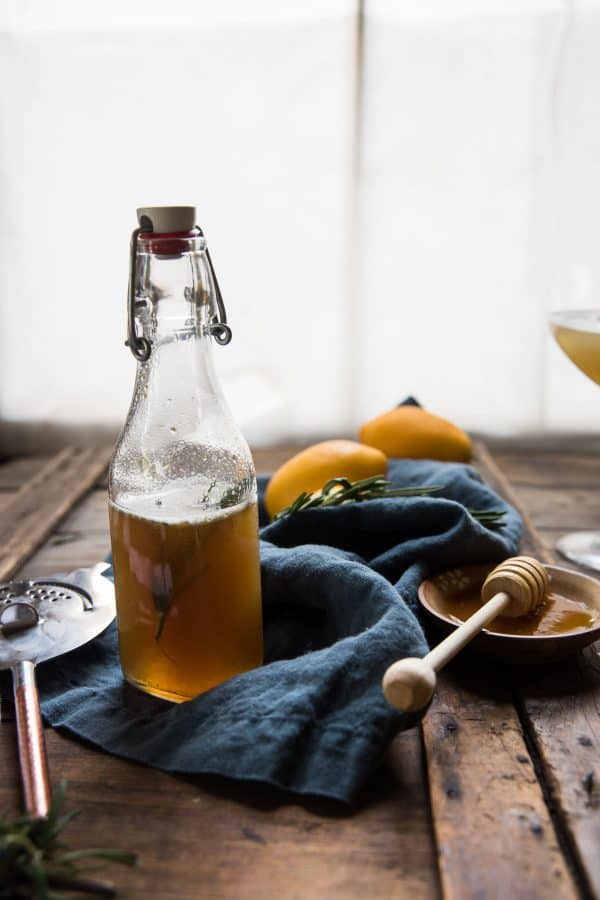 side angle view of rosemary infused honey simple syrup in a glass pourer