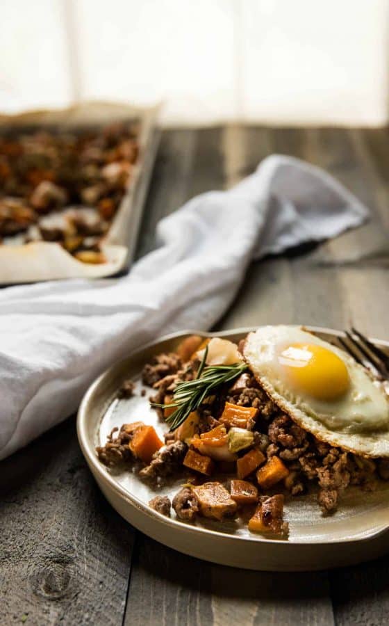 sweet potato hash with lamb and apples on a plate topped with a fried egg