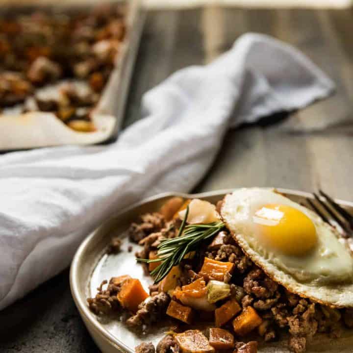 sweet potato hash with lamb and apples on a plate topped with a fried egg