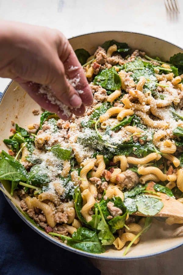 sprinkling parmesan cheese over cavatappi pasta