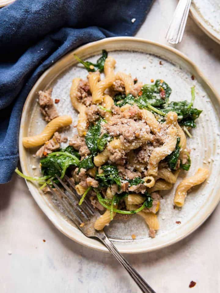 cavatappi shaped pasta with baby kale and sausage on a plate