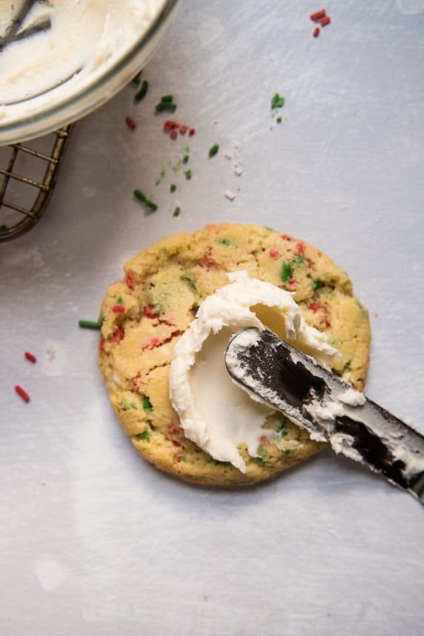 spreading frosting on sprinkle cookies