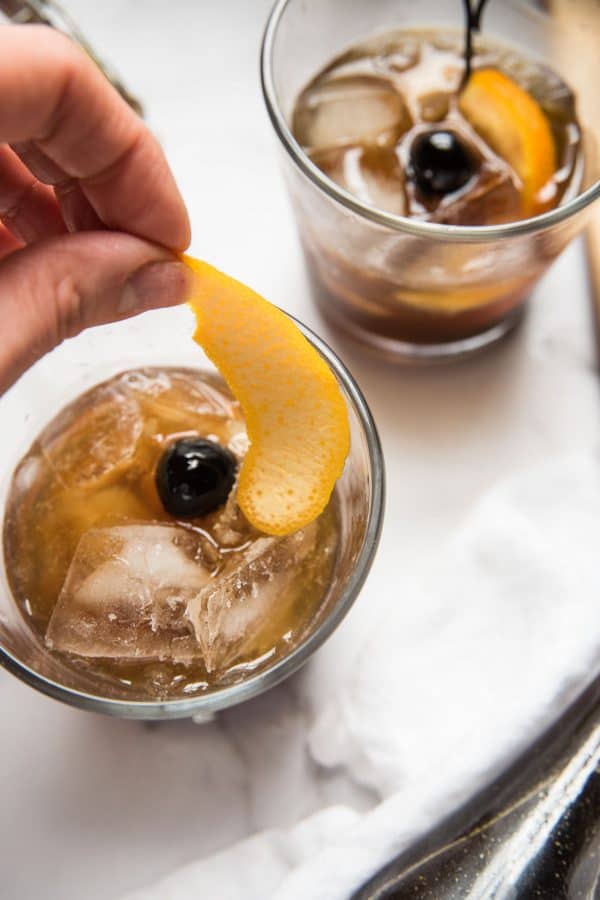 Orange peel being placed inside a gingerbread old fashioned