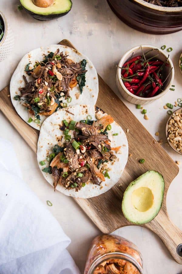 overhead of tortillas getting loaded up with korean beef tac o toppings