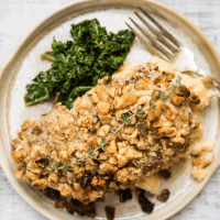 walnut crusted pork chop on a plate with kale and mashed potatoes