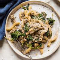 overhead view of chickpea pasta with turkey sausage and kale on a round plate