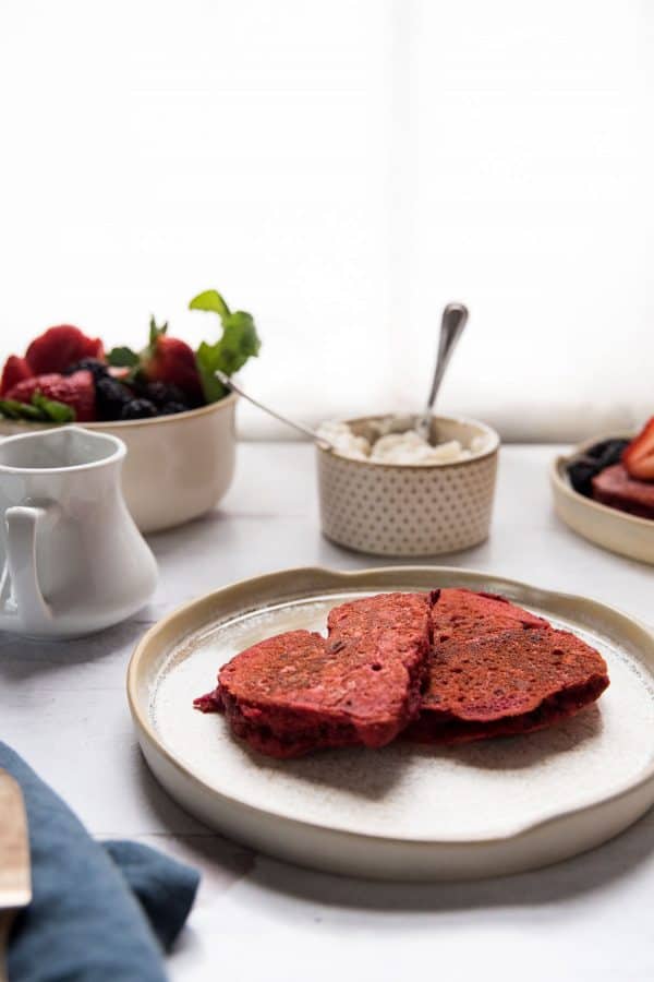 side angle of two heart shaped red pancakes on a plate