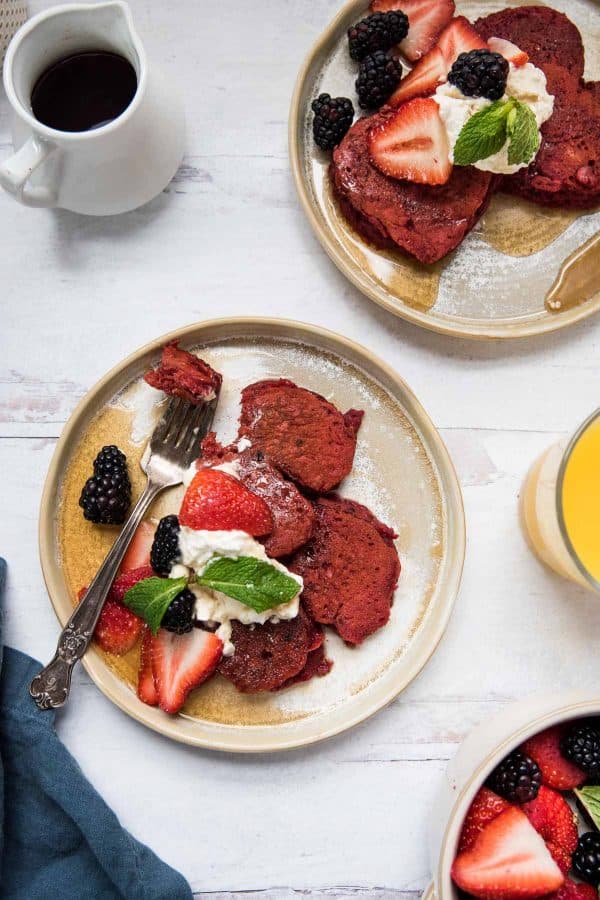 heart shaped pancakes on a plate topped with fresh fruit whipped cream and maple syrup