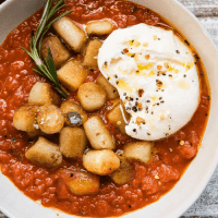 pan seared gnocchi sitting on marinara with a ball of burrata