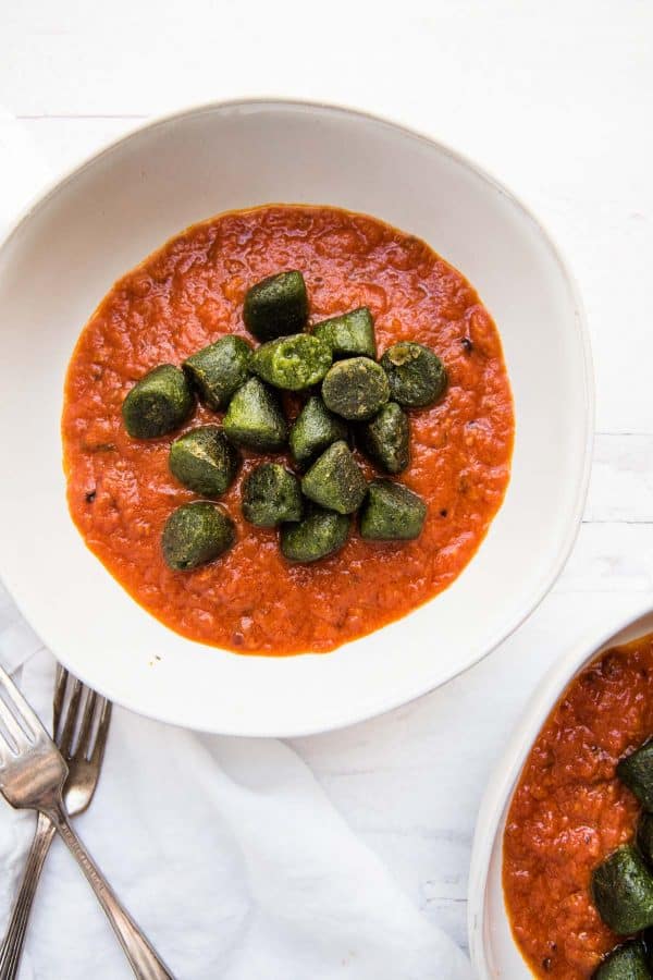 plain kale gnocchi over a bowl filled with red sauce