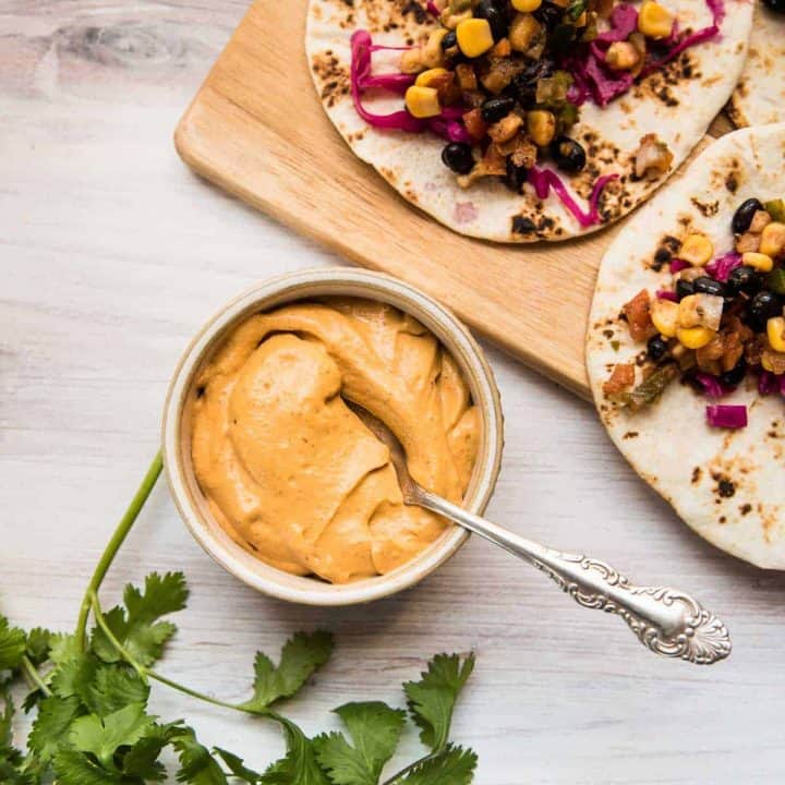 ramekin of orange sauce and two tacos