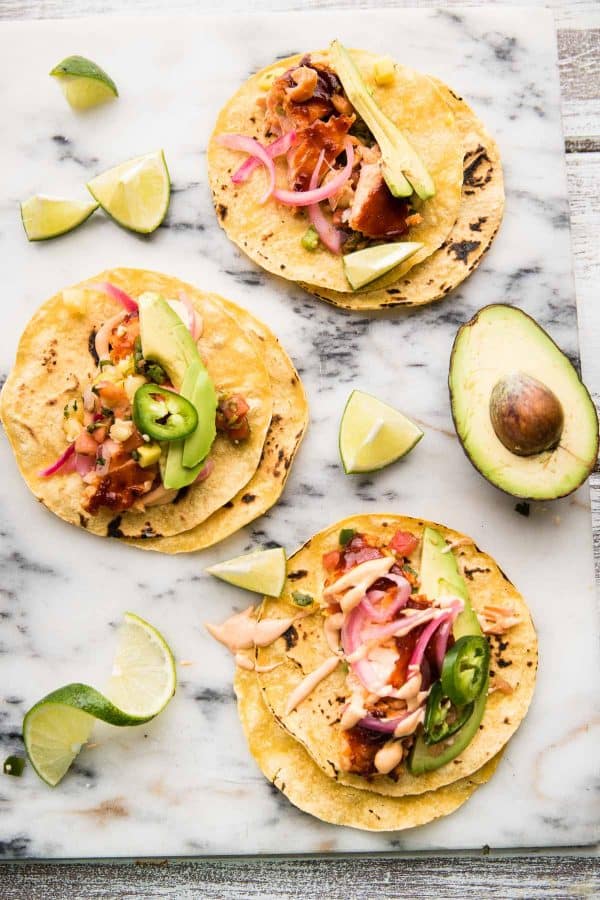 overhead of chipotle bbq fish tacos with avocado and lime